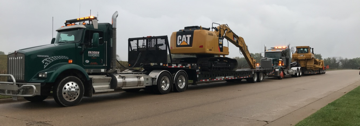 Unzicker Equipment flatbed carrying a piece of heavy equipment